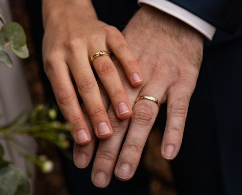 Hochzeitsfotos der Hände der Brautleute mit Eheringen